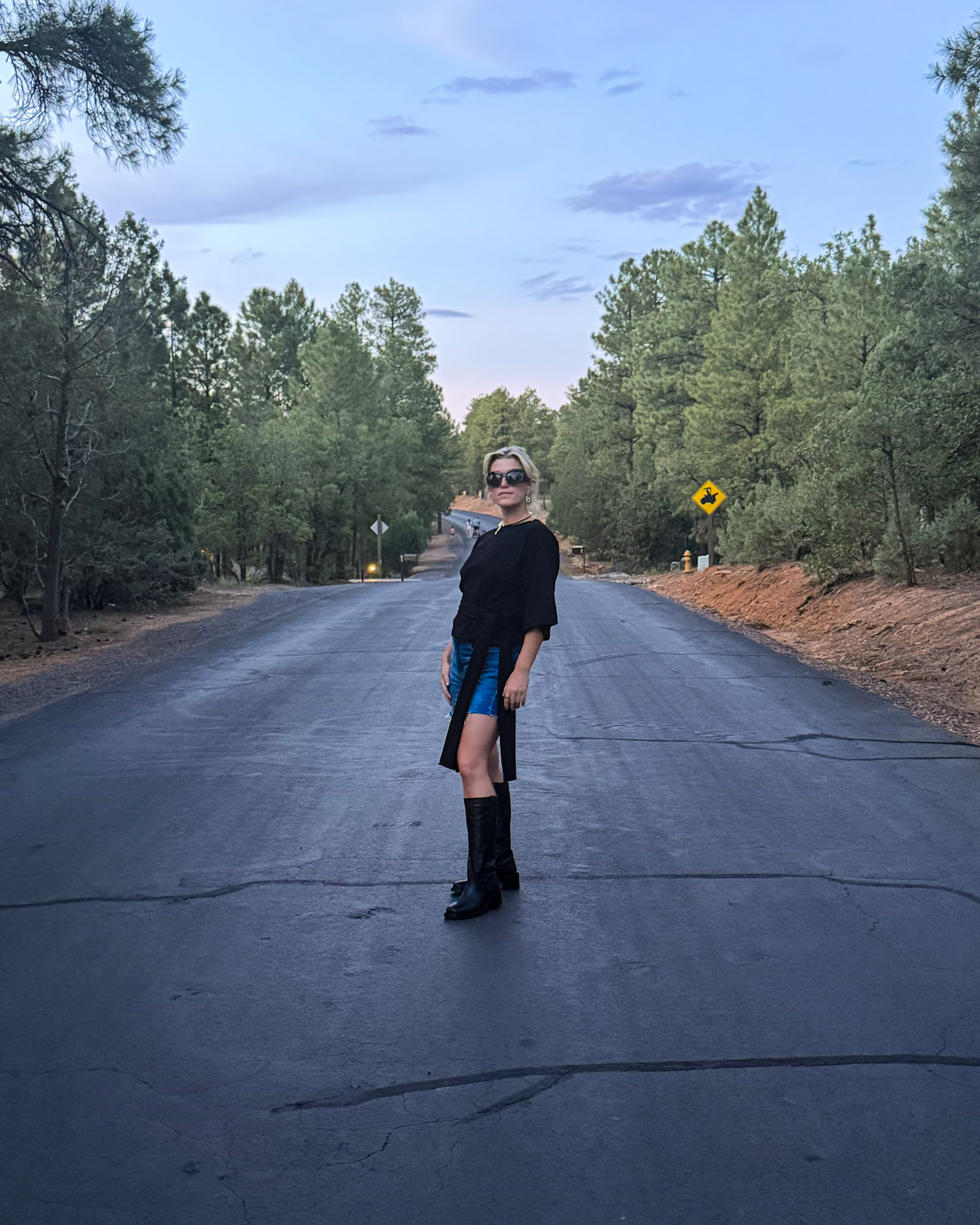 Black wrap top tied at the waist, denim shorts, tall black boots